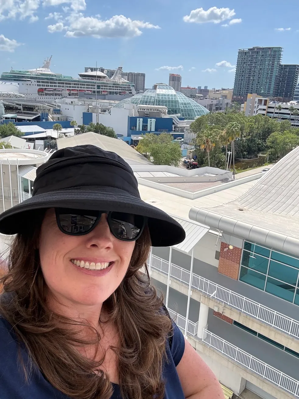 Kate Spilsbury smiling in a sun hat at a port city