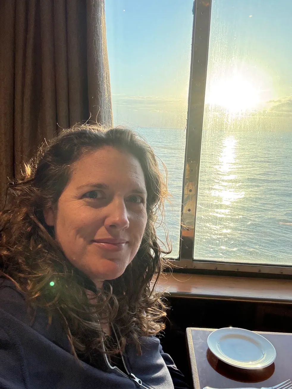 Kate by a cruise ship window at sunset